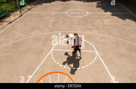 High Angle View von Rückwand des jungen sportlichen Paar spielen Basketball auf Freiplatz am sonnigen Tag Stockfoto