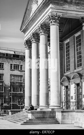 Paar sitzt am Treppenhaus vor Stein Säulen von Leeds Civic Hall, Leeds City Council Building zu sprechen Stockfoto