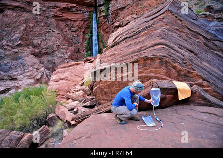 Männliche Wanderer filtert das Wasser auf einer Klippe eingeklemmt Terrasse in der Nähe von Deer Creek Falls im Grand Canyon außerhalb Fredonia, Arizona November 2011. Stockfoto