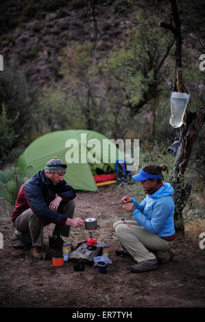 Frau und Mann Rucksacktouristen Vorbereitung Abendessen mit einem Campingkocher im Camp in der Nähe Charleboise Quellen in La Barge Canyon auf den Holländers Weg im Wildnisgebiet Aberglaube, Tonto National Forest in der Nähe von Phoenix, Arizona November 2011. Stockfoto