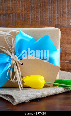 Happy Fathers Day oder maskuline Geburtstag, natürliche Kraft-Papier eingewickelt Geschenk mit blassen blauen Band auf dunklem Holz. Stockfoto