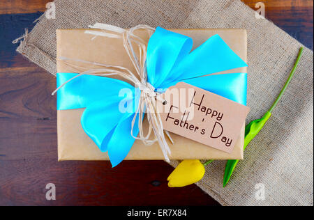 Happy Fathers Day natürliche Kraftpapier umwickelt Owith blass blau Geschenkband auf dunklem Holz. Stockfoto