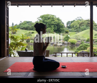 Junge Japanerin trinken von grünem Tee im Teehaus, Suizenji Jojuen Park, Kumamoto City Kokin-Denju-keine-Ma Stockfoto