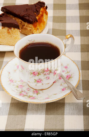 Nahaufnahme des alten porzellanbechers und der Untertasse mit schwarzem Kaffeetee und Stückchen Schokoladenkuchen Stockfoto
