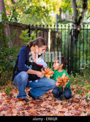 Junge und Mama spielt im Herbstlaub Stockfoto