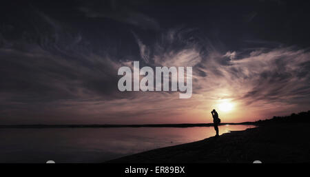 Silhouette-Mann stehend am Seeufer bei Sonnenuntergang, See Aydar, Usbekistan Stockfoto