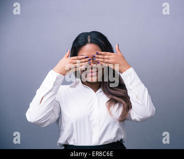 Glücklich afrikanischen Geschäftsfrau, die in ihren Augen über grauen Hintergrund Stockfoto
