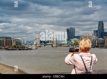 Ein Tourist mit dem Fotografieren von der Themse nach Westen in Richtung Tower Bridge und das Walkie Talkie Gebäude, London, UK Stockfoto