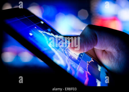 Eine Person, die Börsendaten auf einem mobilen Gerät zu überprüfen. Stockfoto