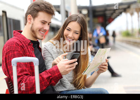 Touristen-Reisende, Beratung, Gps und Führer über ein Smartphone in einem Bahnhof Stockfoto