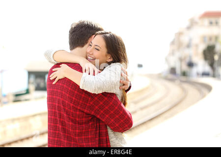 Glückliches Paar umarmt in einem Bahnhof nach Ankunft Stockfoto