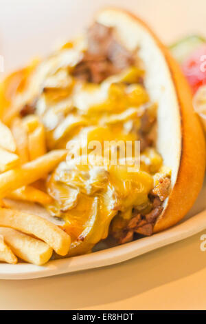 Eine unordentliche Philly Cheesesteak mit Zwiebeln und Paprika mit Pommes Frites auf der Seite Stockfoto