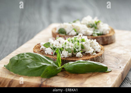 Roggen-Sandwich oder Bruschetta mit Ricotta, Kräutern und Basilikum Stockfoto