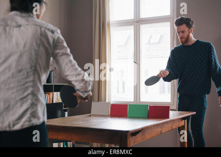 Junger Mann mit Frau zu Hause Tischtennis spielen Stockfoto