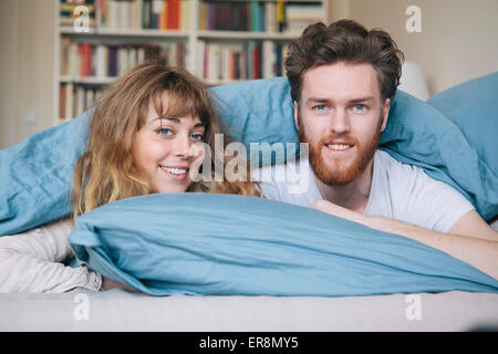 Porträt des jungen Brautpaares im Bett liegend Stockfoto