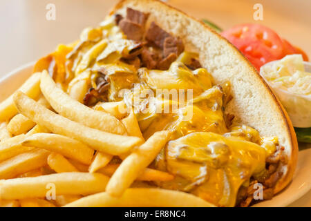 Eine unordentliche Philly Cheesesteak mit Zwiebeln und Paprika mit Pommes Frites auf der Seite Stockfoto