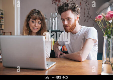 Junges Paar Blick auf Laptop auf Tisch Stockfoto