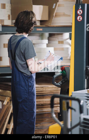 Seitenansicht der junge Arbeiter schreiben auf Papier im Lager Stockfoto