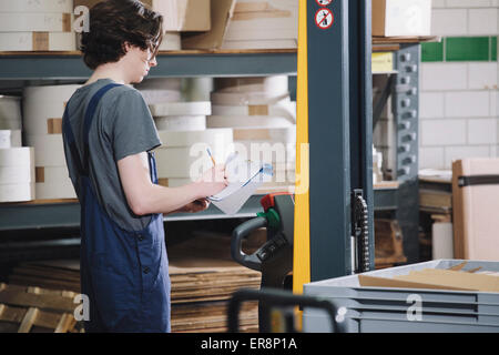 Seitenansicht der jungen Arbeitnehmer schriftlich auf Papier im Lager Stockfoto