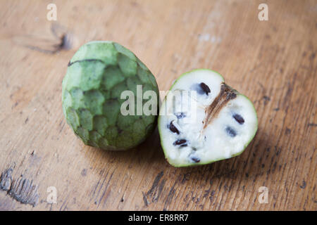 Vogelperspektive Blick auf ganze und halbierte Cherimoya auf Holztisch Stockfoto