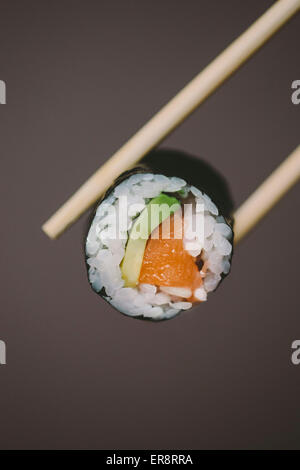 Essstäbchen mit Sushi gegen grauen Hintergrund Stockfoto