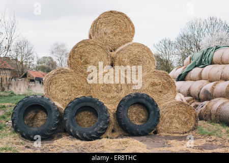 Gestapelten Heuballen und Reifen auf Bauernhof Stockfoto