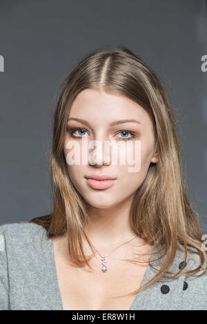 Porträt der schönen jungen Frau vor grauem Hintergrund