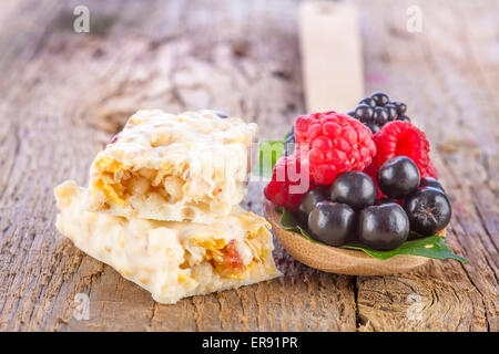 Müsliriegel mit frischen Beeren in Löffel auf hölzernen Hintergrund Stockfoto