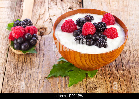 Joghurt mit Waldbeeren in Holzschale auf hölzernen Hintergrund Stockfoto