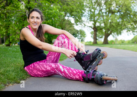 junge Frau, die ihre Rollerblades Befestigung Stockfoto