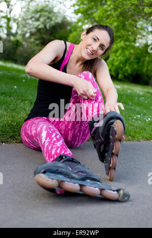 junge Frau, die ihre Rollerblades Befestigung Stockfoto