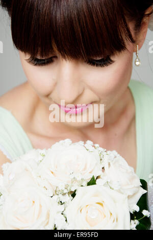 Braut posiert nach dem Aufstehen Profi machen für ihren Hochzeitstag, schönes Gesicht und Blumenstrauß Closeup. Braut hat Pony. Stockfoto