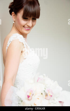 Braut posiert mit ihrem Bouquet nach dem Aufstehen Profi machen für ihren Hochzeitstag. Braut hat Pony. Stockfoto