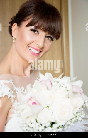 Braut posiert mit ihrem Bouquet nach dem Aufstehen Profi machen für ihren Hochzeitstag. Braut hat Pony. Stockfoto