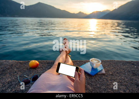 Frau mit Telefon liegen am pier Stockfoto