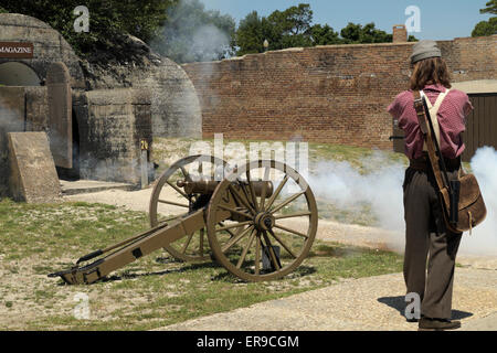 Mann im Bürgerkrieg Gewand zeigt laden und Abfeuern einer Vintage Kanone im Fort Gaines. Stockfoto