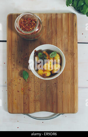 Frisch zubereitete Bio-Kartoffeln mit Gewürzen in einer Schüssel auf einem Vintage Holztisch. Retro-Farben Stockfoto