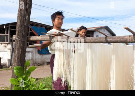 In Hsipaw, Birma sind frisch gekochten Reisnudeln auf Masten an der frischen Luft trocknen nach unternommen in den Gebäuden hinter aufgehängt. Stockfoto