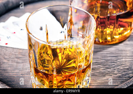 Glas und Karaffe aus Schnaps und vier Asse auf Holzfass Stockfoto