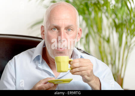 ein Mann mittleren Alters Kaffeetrinken auf seinem sofa Stockfoto