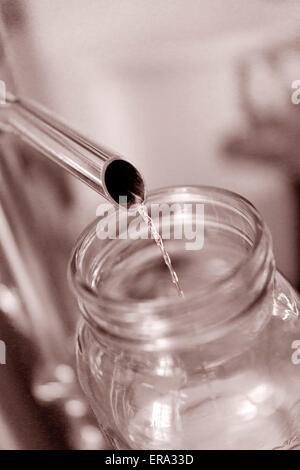 Alkohol in Test Glas bei handwerklichen Brennerei gießen. Vertikale Sepia Farbfoto in Key West Schnapsbrennen, Florida, USA Stockfoto