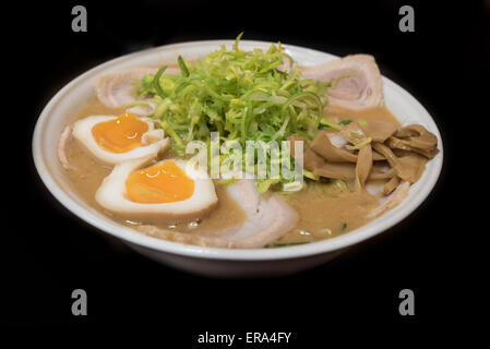 Nahaufnahme von einem Ramen Nudelsuppe mit Porc, Schnittlauch, Eiern, Bambus und Lauch auf schwarzem Hintergrund isoliert Stockfoto
