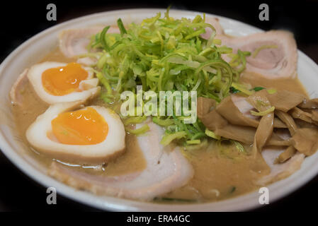 Nahaufnahme von einem Ramen Nudelsuppe mit Porc, Schnittlauch, Eiern, Bambus und Lauch auf schwarzem Hintergrund isoliert Stockfoto