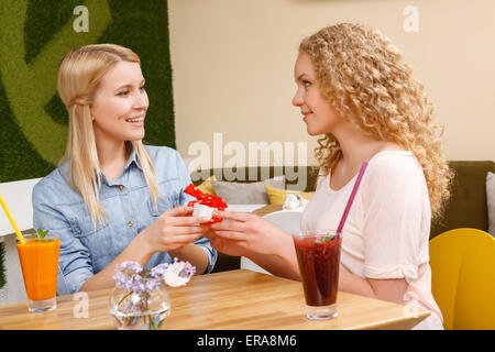 Zwei Mädchen geben einander präsentiert im café Stockfoto