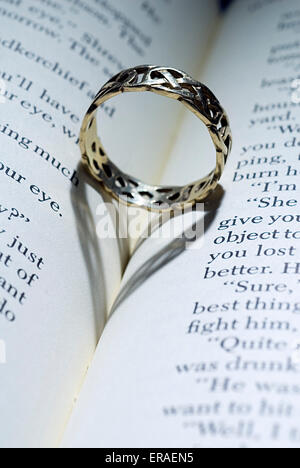 Ring mit herzförmigen Schatten auf ein offenes Buch liegend