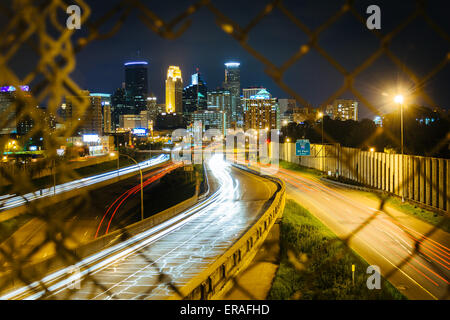 Maschendrahtzaun und Blick auf i-35 und die Skyline bei Nacht, gesehen von der 24th Street Fußgängerbrücke in Minneapolis, Minneso Stockfoto