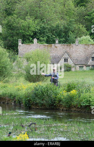 Mann-Fliegenfischen auf dem Fluss Coln vor Arlington Row, Bibury, Cotswolds, Gloucestershire, England Stockfoto