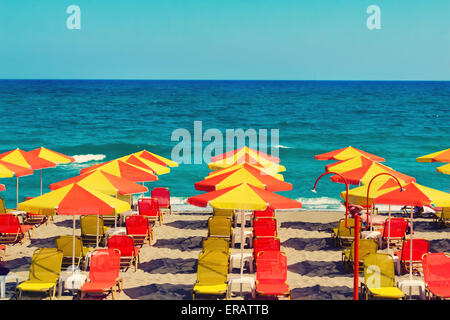 Schirme für Sonnenschutz und Sonnenliegen am menschenleeren Strand wegen des Sturms. Auf den Wellen des Meeres. Stockfoto