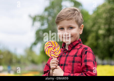 glücklich kleiner Junge mit großen Süßigkeiten im freien Stockfoto