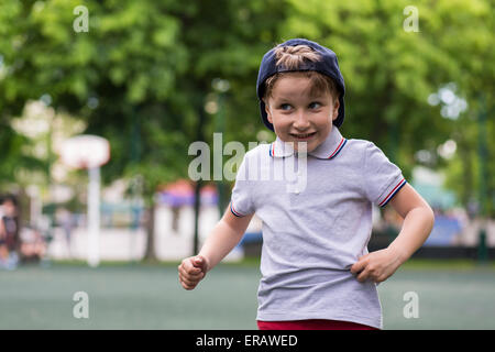 Glückliche kleine Junge lächelnd jemanden im Park begrüßen Stockfoto